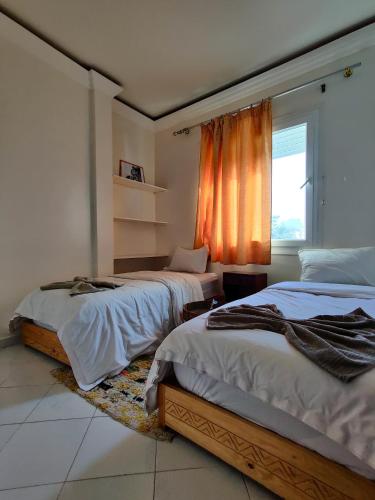 a bedroom with two beds and a window at Locals Taghazout surfcamp in Taghazout
