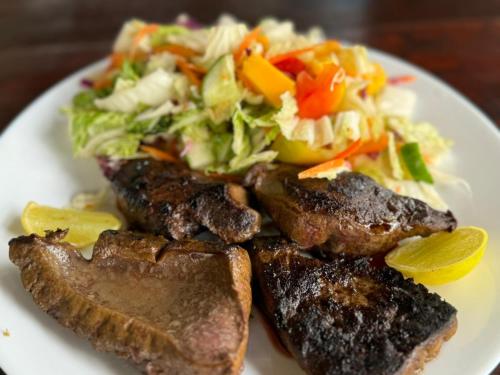 a plate of food with meat and a salad at Bay Dreams Beach Hotel & Surf Camp in Arugam Bay