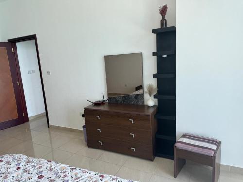 ein Schlafzimmer mit einer Kommode und einem Spiegel in der Unterkunft Corniche Residence Tower in Ajman 