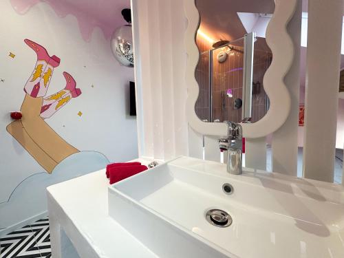 a bathroom with a white sink and a mirror at Chambre Disco Paradisio in Sélestat