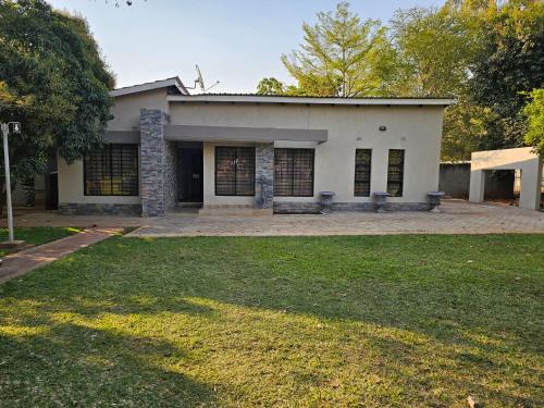 a white house with two benches in a yard at Grananda Villas # 83E in Lusaka