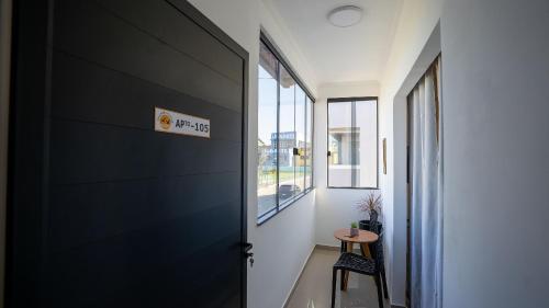 a hallway with a black door and a table at Acesso à Praia Ar Condicionado Conforto Garantido! in Saquarema