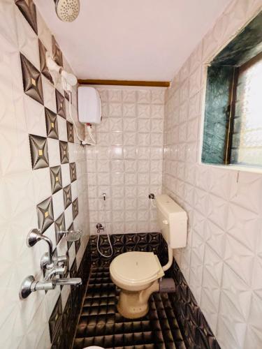 a bathroom with a toilet and a tiled floor at Sai Ekvira Farms in Surai