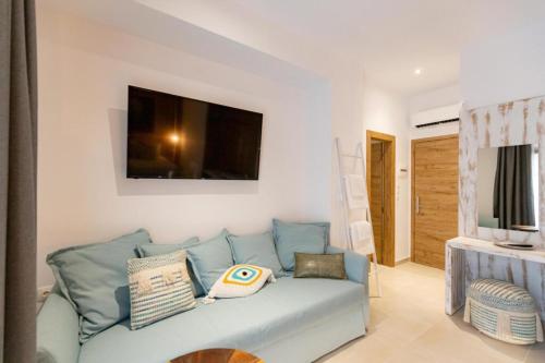 a living room with a blue couch and a television at Blue Sea Suites in Afitos