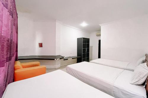 a hotel room with two beds and an orange chair at Scala Inn By Helocus in Medan