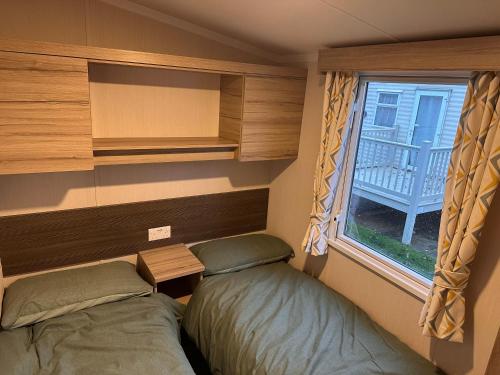 a small bedroom with two beds and a window at 3BR-Sleeps6-Parking-Pool-NearBeach&Skegness in Skegness