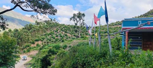 a car driving down a dirt road next to flags at Aamis Home Stay in Vattavada
