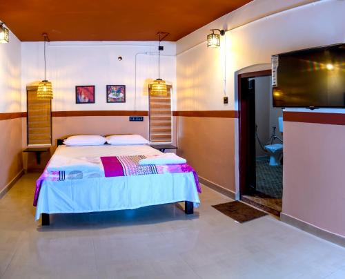 a bedroom with a bed and a flat screen tv at Rams Guest House Samudra-Walk to Cliff,Odayam,Black Beach Varkala in Varkala