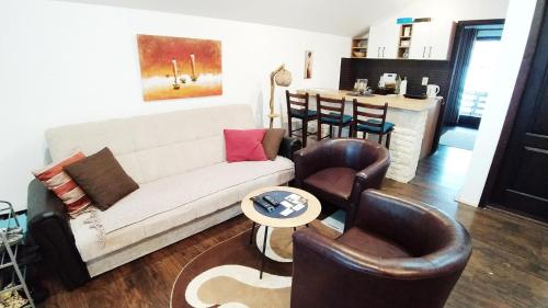 a living room with a white couch and leather chairs at Apartman Draškovic - Goč in Biserske Kuće