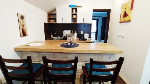 a kitchen with a counter with four chairs around it at Apartman Draškovic - Goč in Biserske Kuće