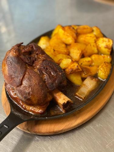 a plate of food with a piece of meat and potatoes at Hanul Lui Bogdan Economy INN in Făget