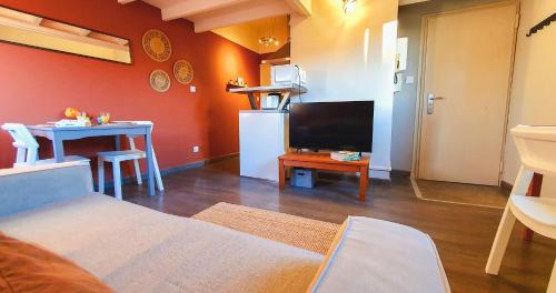 un salon avec une télévision et une petite table avec une table dans l'établissement Le nid des Teinturiers - rooftop view - AC, à Avignon