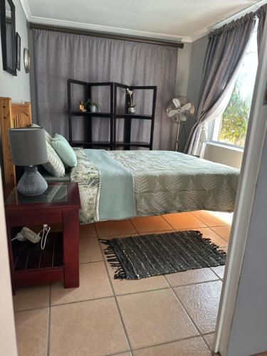 a bedroom with a bed and a table and a window at ChezBelle, self-catering 2 sleeper in Constantia with self check-in in Cape Town