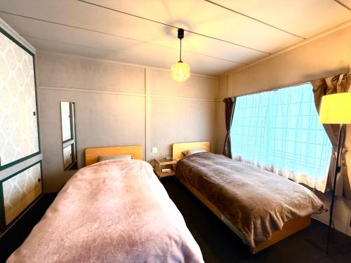 a bedroom with two beds and a window at 蒼穹 in Asahikawa