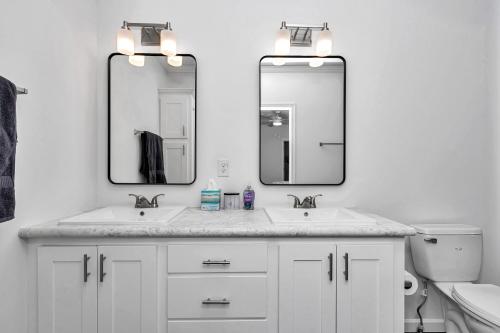 a white bathroom with two sinks and two mirrors at Pony Flat in Ocala