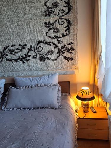 a bed with a blanket and a lamp on a night stand at Pirin Golf hotel, Apartment Chalet style in Razlog