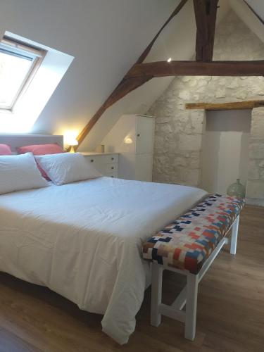 - une chambre avec un lit blanc et un banc dans l'établissement Au jardin de Florentine, à Ingrandes-de-Touraine