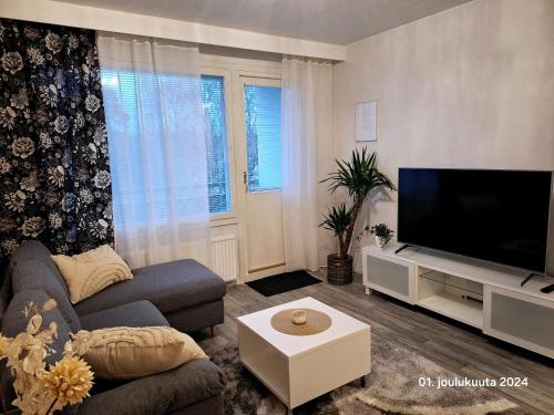 Una sala de estar con un sofá y un televisor de pantalla plana. en Tyylikäs kaksio keskustasta parkkipaikalla,wifi, en Lappeenranta