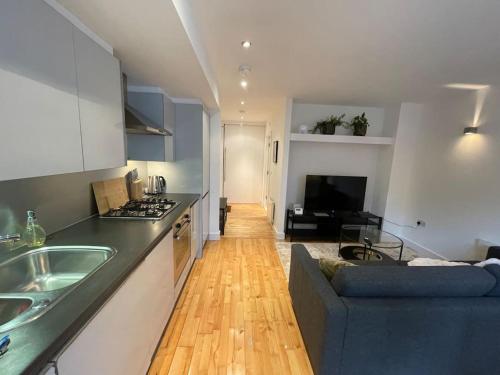 a kitchen and living room with a blue couch in a room at Fabulous Leeds City Center Urban Loft in Leeds