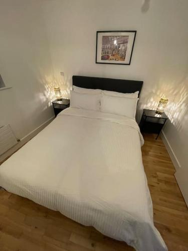 a bedroom with a large white bed with two lamps at Fabulous Leeds City Center Urban Loft in Leeds