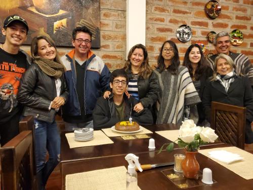 a group of people standing around a table with a cake at Balcon al Cotopaxi Hosteria in Sangolquí