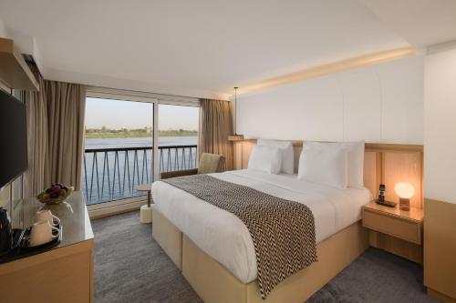a hotel room with a bed and a balcony at Tamr Nile Cruise - 04 Nights Every Monday from Luxor - 03 Nights Every Friday from Aswan in Luxor