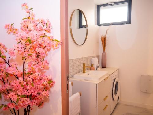 a bathroom with a sink and a tree with pink flowers at Les Gites d'Andréa- Chez les Fifou in Surba