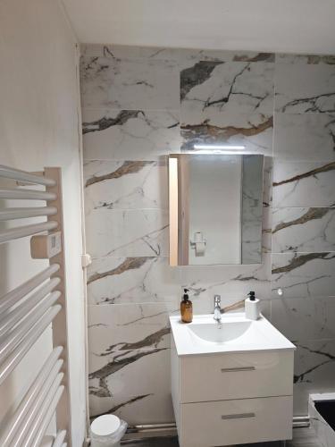 La salle de bains est pourvue d'un lavabo blanc et d'un mur en marbre. dans l'établissement Le République Grand Studio Wi-Fi / Netflix, à Angoulême