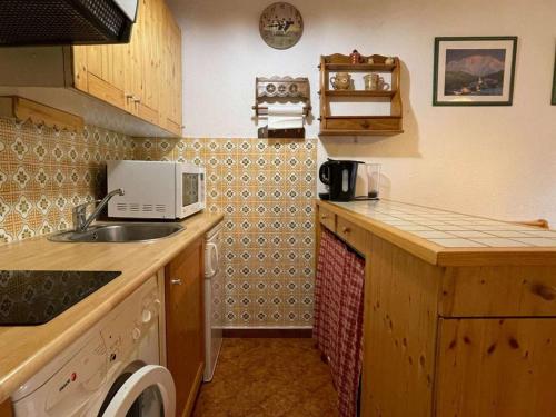 une petite cuisine avec un évier et un micro-ondes dans l'établissement Studio montagnard pour 4 à 5 min des commerces avec ski bus au pied - FR-1-458-119, au Grand-Bornand
