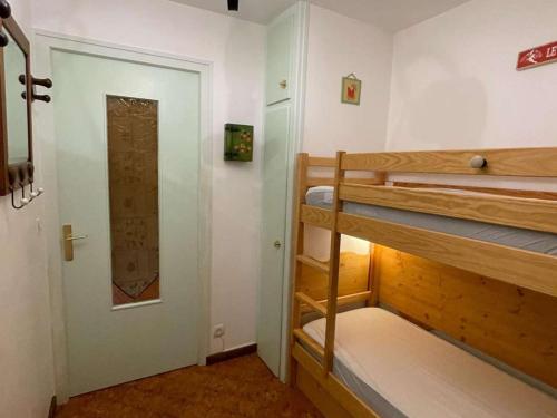 Cette chambre comprend 2 lits superposés et une porte. dans l'établissement Studio montagnard pour 4 à 5 min des commerces avec ski bus au pied - FR-1-458-119, au Grand-Bornand