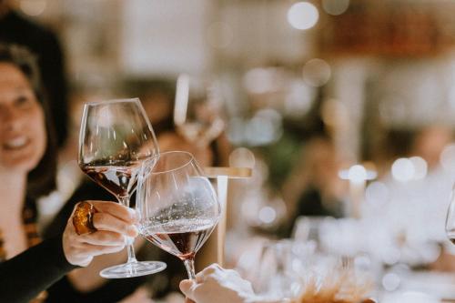 two people holding up glasses of red wine at Hotel Aurora in Merano