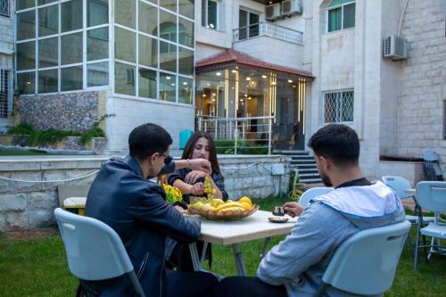 a group of three people sitting at a table with bananas at فندق الفاروق in Ash Shumaysānī