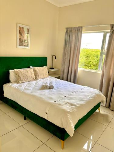 a bedroom with a bed with a green headboard and a window at The Beacon Fairy in East London