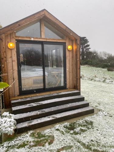a small wooden cabin with stairs in the snow at Otterly's Retreat in Skibbereen