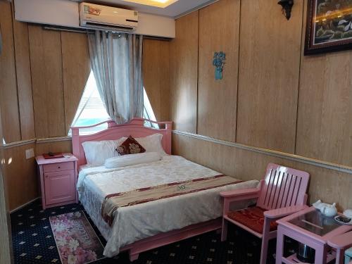 a small bedroom with a pink bed and a chair at Nhat Quy Hotel in Tây Ninh