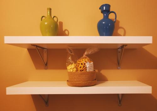 two white shelves with vases and a basket on them at Alle Luminarie in Bari