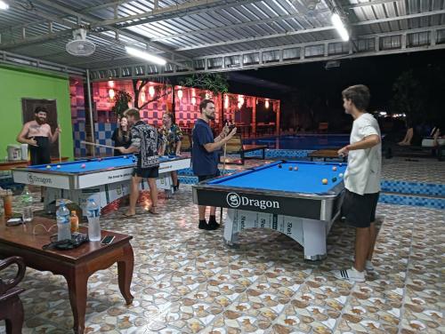 a group of people standing around pool tables at Vang Vieng Sabai Sabai Hostel in Vang Vieng