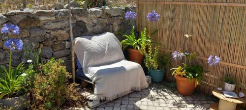 acovered chair with a blanket in a garden with plants at Casa da Marianne in Sintra