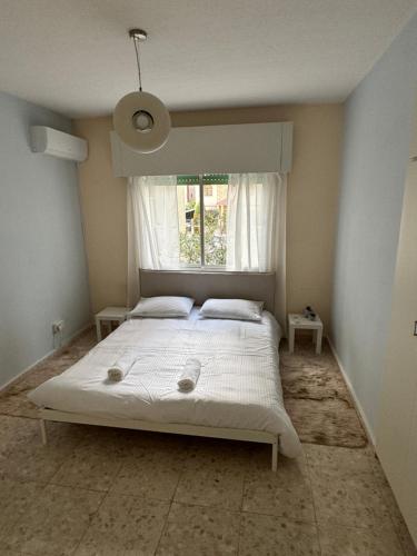 a bedroom with a white bed with a window at Georges 2 Bedroom Apartment in Limassol