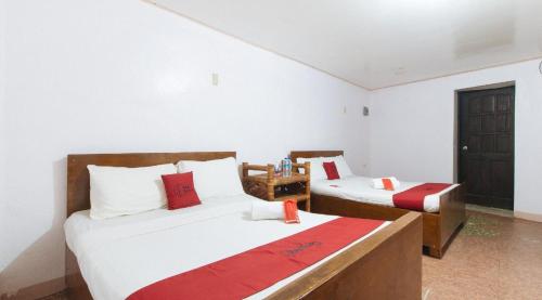 a bedroom with two beds with red and white pillows at RedDoorz Hostel at Megans Paradisio Beach Resort in Zambales