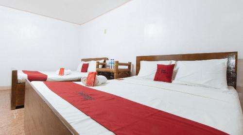 two beds in a room with red and white at RedDoorz Hostel at Megans Paradisio Beach Resort in Zambales