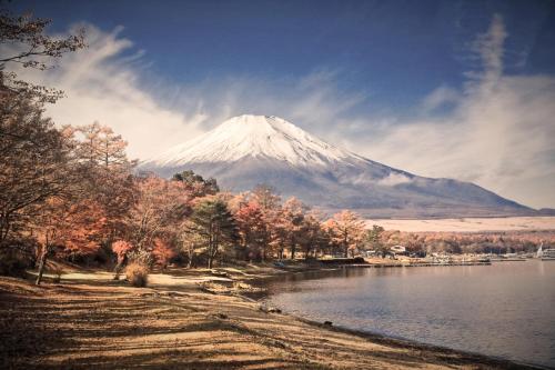a snow covered mountain sitting next to a body of water at Sansui Resorts Yamanakako in Yamanakako