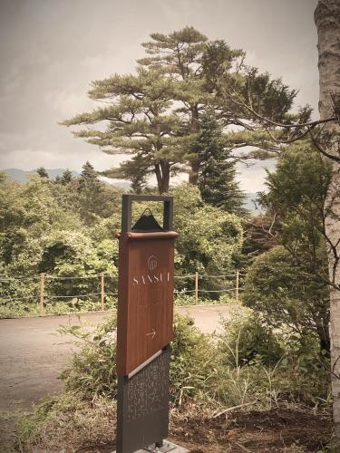a wooden box with writing on it in front of a tree at Sansui Resorts Yamanakako in Yamanakako