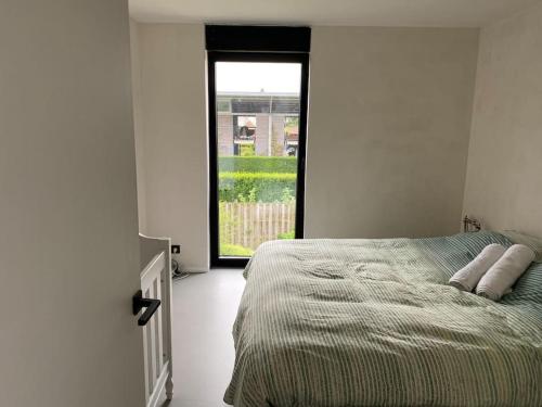 a white bedroom with a bed and a window at Modern spatious house near Bruges in Bruges