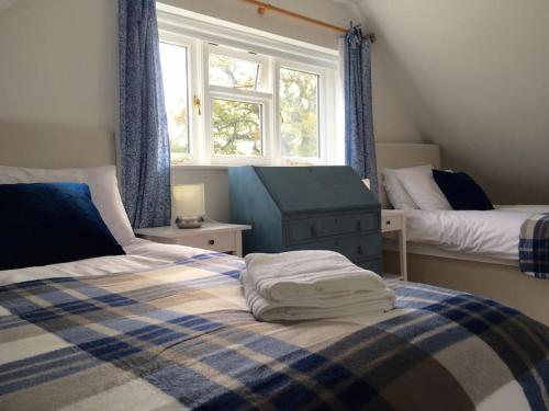 a bedroom with two beds and two windows at New Forest Cottage in Lyndhurst