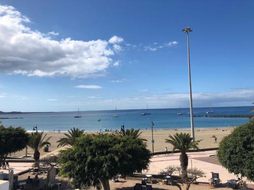 a beach with people and boats in the water at Apartamento Playa Las Vistas in Arona