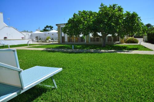 a white bench sitting on a lawn in front of a house at B&B Domus Terra Mare in Torre San Giovanni Ugento