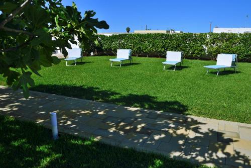 a group of white chairs sitting on the grass at B&B Domus Terra Mare in Torre San Giovanni Ugento