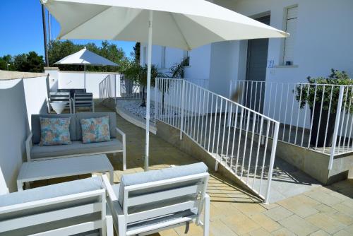 a patio with two chairs and an umbrella at B&B Domus Terra Mare in Torre San Giovanni Ugento
