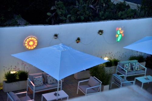 a patio with an umbrella and chairs and a wall at B&B Domus Terra Mare in Torre San Giovanni Ugento
